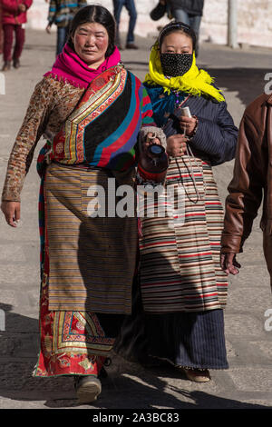 Deux femmes tibétaines les pèlerins en costumes traditionnels, y compris leur bangdian pangden colorés ou tabliers, visitez le monastère de Drepung, près de Lhassa, au Tibet. Banque D'Images