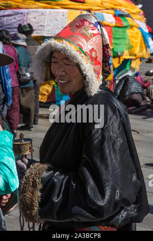 Une femme tibétaine Khamba pilgrim du Kham, région est du Tibet avec son moulin à prières et portant un chapeau de fourrure traditionnel et chuba manteau. Banque D'Images