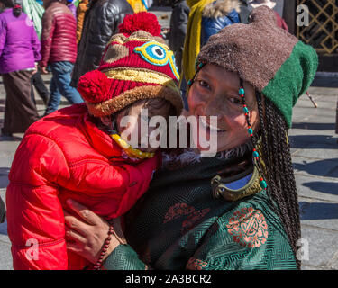 Un Khamba femme de la tibétaine du Kham, région est du Tibet porte son jeune enfant comme elle circumambulates autour du temple du Jokhang à Lhassa, au Tibet. Banque D'Images