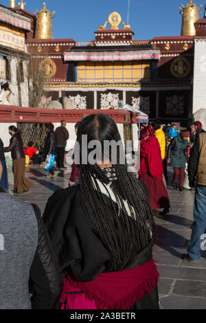 Une vieille femme circumambulates pèlerin tibétain le Temple de Jokhang, avec ses cheveux en petites tresses. Lhassa, Tibet. Porte la robe traditionnelle chupa. Banque D'Images