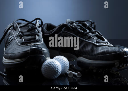 Balles de golf, tees et chaussures isolé sur fond bleu foncé. Banque D'Images