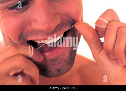 Jeune homme de la soie dentaire dents, Close up Banque D'Images