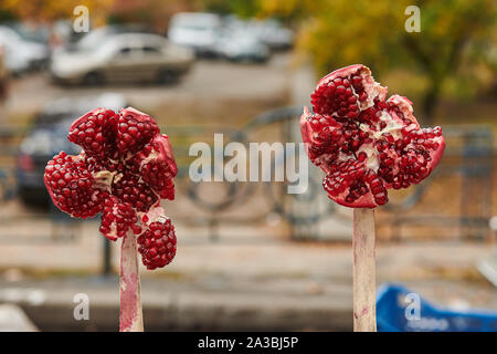 Ouvert deux grenades sur les bâtons au marché. Dégustation de fruits mûrs. Santé Naturelle de produit. Graines rouges. Bokeh avec gros plan. Banque D'Images