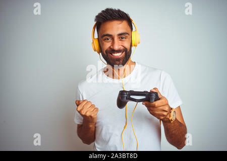 Les indiens arabes gamer man playing video game de l'utilisation des écouteurs sur fond blanc isolé crier fier et célébrer la victoire et le succès très exci Banque D'Images