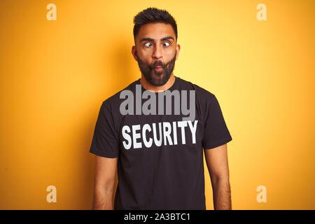 Sauvegarde hispanique indienne arabe homme portant un uniforme de sécurité sur fond jaune isolé fait face avec les lèvres, fou et geste comique. Fun Banque D'Images