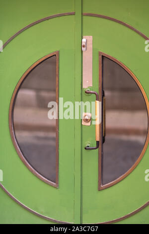 Porte verte colorés avec des fenêtres en verre circulaire et manipuler dans un close up portrait avec des réflexions sur la vitre Banque D'Images