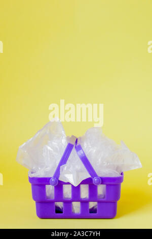 Sacs en polyéthylène dans panier sur fond jaune. Banque D'Images