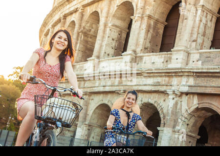 Deux jeunes femmes heureux amis touristes avec des vélos à Colisée à Rome, Italie au lever du soleil. Banque D'Images