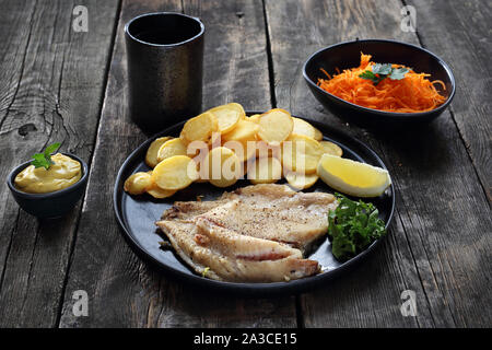 Filet de poisson grillé servi avec pommes de terre au four, salade de carottes et de la sauce Banque D'Images