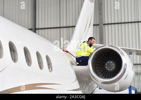 Mécanicien d'aéronefs inspecte et vérifie la technologie d'un jet dans un hangar à l'aéroport Banque D'Images