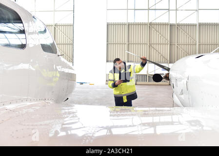Mécanicien d'aéronefs inspecte et vérifie la technologie d'un jet dans un hangar à l'aéroport Banque D'Images