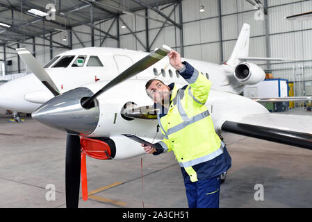 Mécanicien d'aéronefs inspecte et vérifie la technologie d'un jet dans un hangar à l'aéroport Banque D'Images