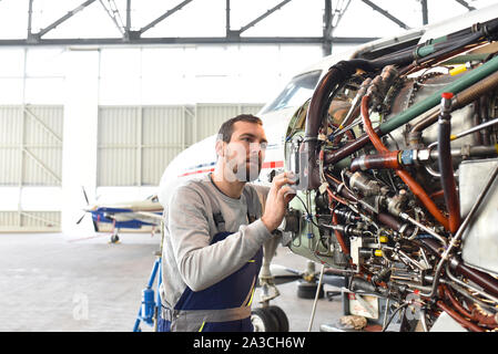 Mécanicien d'aéronefs répare un moteur d'avion dans un hangar de l'aéroport Banque D'Images