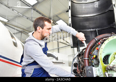 Mécanicien d'aéronefs répare un moteur d'avion dans un hangar de l'aéroport Banque D'Images