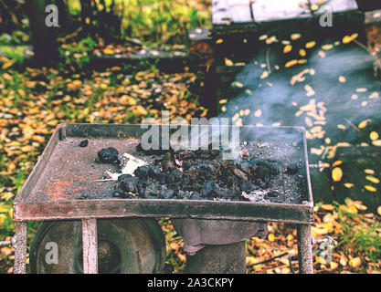 Four portable ouvert de maréchaux-ferrants. La combustion du charbon dans le four, éteint le feu dans la région de four de forge, lieu de travail temporaire. Concept d'backsmithing Banque D'Images