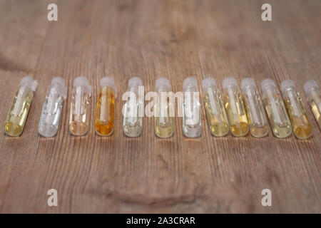Groupe de petites bouteilles de verre sur fond de bois. Testeurs de parfum ou d'échantillons chimiques. Vue de côté. Soft focus sélectif. Profondeur de champ. Text Banque D'Images