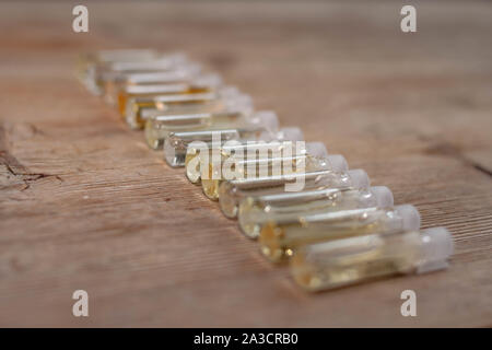 Groupe de petites bouteilles de verre sur fond de bois. Testeurs de parfum ou d'échantillons chimiques. Vue de côté. Soft focus sélectif. Profondeur de champ. Text Banque D'Images
