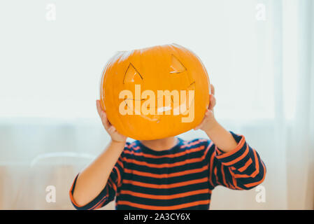 Petit garçon fait Halloween Pumpkin head à la maison Banque D'Images