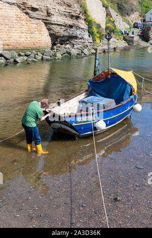 Un pêcheur qui tend ses coble dans le beck à Staithes Banque D'Images