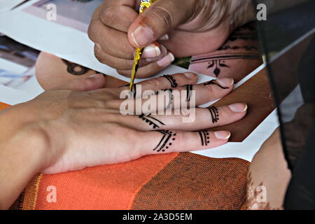 L'application de l'artiste tatouage au henné sur les mains des femmes. Décoration traditionnelle indienne est Mehndi art. Close-up Banque D'Images