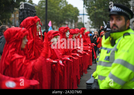 Les manifestants, surnommés les rebelles Rouge, à l'extérieur de l'armoire Bureau sur Whitehall, au cours d'une rébellion d'Extinction (XR) Manifestation à Westminster, Londres. Banque D'Images
