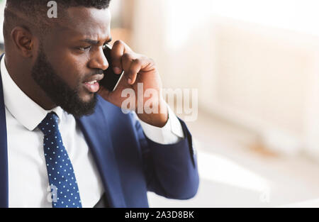 Furious businessman talking par smartphone avec partenaires Banque D'Images