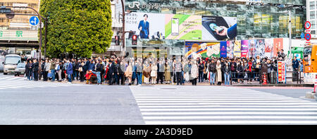 Tokyo. Shibuya. Le célèbre passage scramble. Voir en face des gens de l'extérieur de la gare JR de Shibuya en attente de lumières pour changer de traverser la route. Banque D'Images