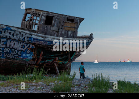 Un vieux bateau de pêche en bois couvert de graffitis sur cale sèche. Banque D'Images