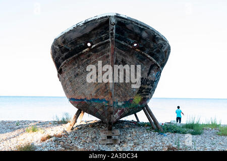 Un vieux bateau de pêche en bois couvert de graffitis sur cale sèche. Banque D'Images