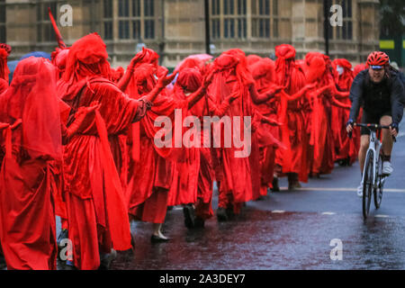 Londres, Royaume-Uni, 06 mai 2019. Suite à la confrontation avec la police, le groupe paisiblement à pied passé les chambres du Parlement. Rébellion d'extinction des militants du groupe 'Brigade' rouge, avec plus de 100 participants, face à un cordon de police à Millbank à Westminster, déplaçant lentement le long de leur ligne et regarder directement officiers, un par un. Credit : Imageplotter/Alamy Live News Banque D'Images