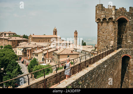 Femme marche sur actif de l'ancienne voie d'observation avec mur de briques en petites tour de ville avec sa chapelle en Toscane Italie Banque D'Images