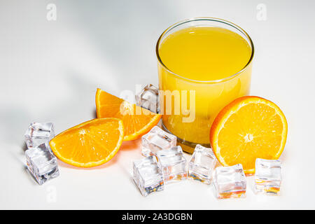 Verre de jus d'orange et des oranges sur un tableau blanc Banque D'Images