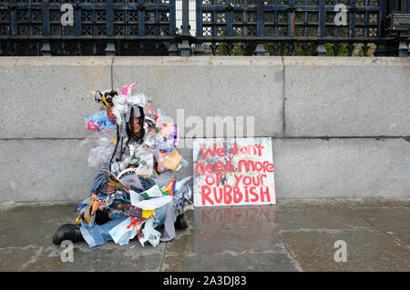 Westminster, London, UK - Lundi 7 octobre 2019 - Rébellion Extinction XR les manifestant portant une tenue faite de déchets se trouve dans la pluie à l'extérieur du Parlement la lecture d'un livre sur Greta Thunberg le jour 1 de la XR de protestation. Photo Steven Mai / Alamy Live News Banque D'Images