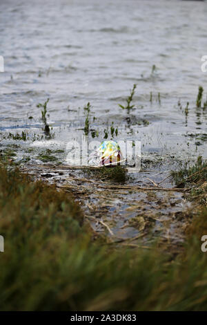 Un ballon d'anniversaire en plastique qui s'est échoué sur une rive du fleuve à la création d'un risque environnemental pour la faune Banque D'Images