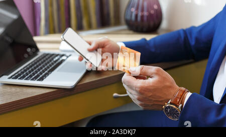 Homme tenant une carte de crédit et téléphone portable, rendant les paiements en ligne Banque D'Images