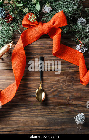Mise en page créative, faite de branches d'arbre et frontière Noël coupe d'or, décoré de ruban rouge sur fond de bois. Mise à plat. Menu alimentaire coopération Noël Banque D'Images