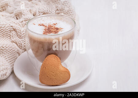 Une tasse de café au lait saupoudré de cannelle et d'un biscuit en forme de coeur Banque D'Images