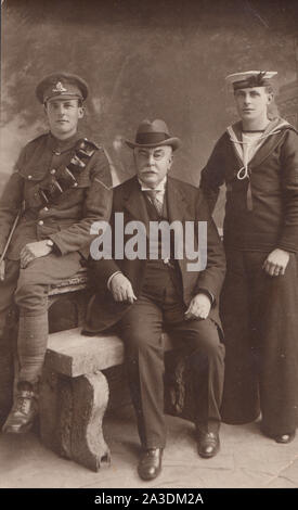 Vintage Début xxe siècle Carte postale photographique montrant un père avec ses deux fils. Un soldat de l'armée britannique de l'Artillerie royale. L'autre fils d'un marin de la marine britannique de S.M.S.Valient. Banque D'Images