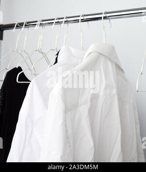 White men's shirts froissé accrochée à un cintre en métal, fond blanc Banque D'Images