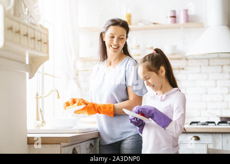 Petite fille aidant à sa mère lave-vaisselle Banque D'Images