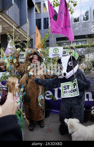 Deux hommes habillés en costumes d'arbres badger et protester contre 1 Eversholt Street, Londres, l'AC de Network Rail, pour essayer de prévenir la perte de 68 anciens bois au cours de l'élaboration de HS2, la liaison ferroviaire à grande vitesse entre Londres et Birmingham, Manchester et Leeds. Ils demandent aux crimes contre nature d'être redéfinie dans la loi comme l'écocide. Rejoint par le public, des militants, la rébellion Extinction Woodland Trust, et les résidents de la localité touchée par le développement, le blaireau n'est porteur d'une affiche disant 'Stop à l'écocide'. Aussi présent sur la journée a été présentateur et naturaliste Chris Packham. Banque D'Images