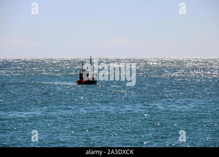 Petit bateau de pêche navigue sur la mer ouverte en début de soirée Banque D'Images