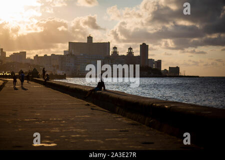 Un homme attend assis sur le Malecon au coucher de soleil à La Havane, Cuba. Banque D'Images