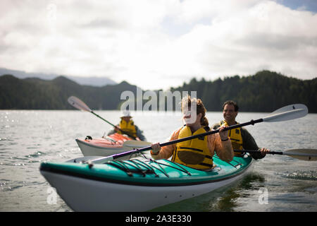 Happy mid-adult couple kayak sur un lac avec leur fils adolescent. Banque D'Images