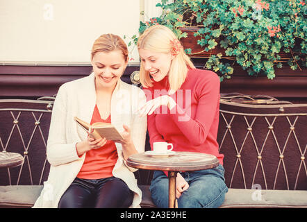 Lecture livre inspirant. L'amélioration d'individu et de l'éducation. Discuter de librairie populaire. Réserver chaque fille devrait lire. Girls friends sitting café terrasse boire du café. La littérature féminine. Banque D'Images