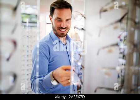 Bel homme choisissant en optique lunettes store. Banque D'Images
