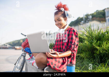 En utilisant son ordinateur portable étudiant bouclés tout en se préparant pour test. Banque D'Images