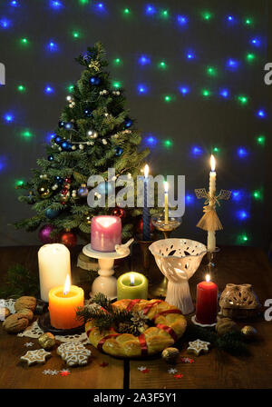 Arbre de Noël, brûler des bougies dans les chandeliers, un pain rituel, d'épices biscuits, les noix sont sur la table en bois. Banque D'Images