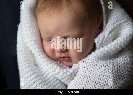 Un mois d'un bébé endormi enveloppé dans une couverture blanche Banque D'Images