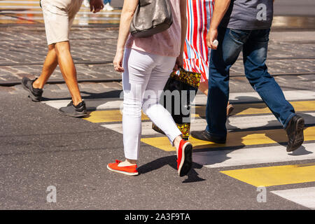 Les jambes de jeunes piétons circulent sur le passage pour piétons dans la ville le jour de l'été Banque D'Images